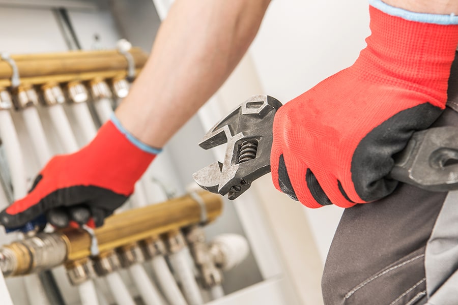 Close-up of plumber's hand using wrench on radiator.