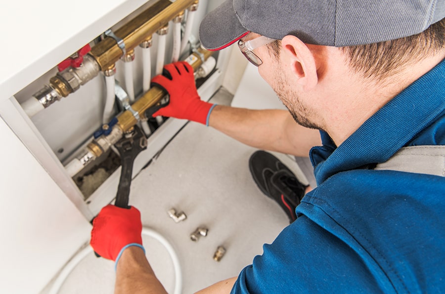 Plumber tightening pipes under sink with wrench